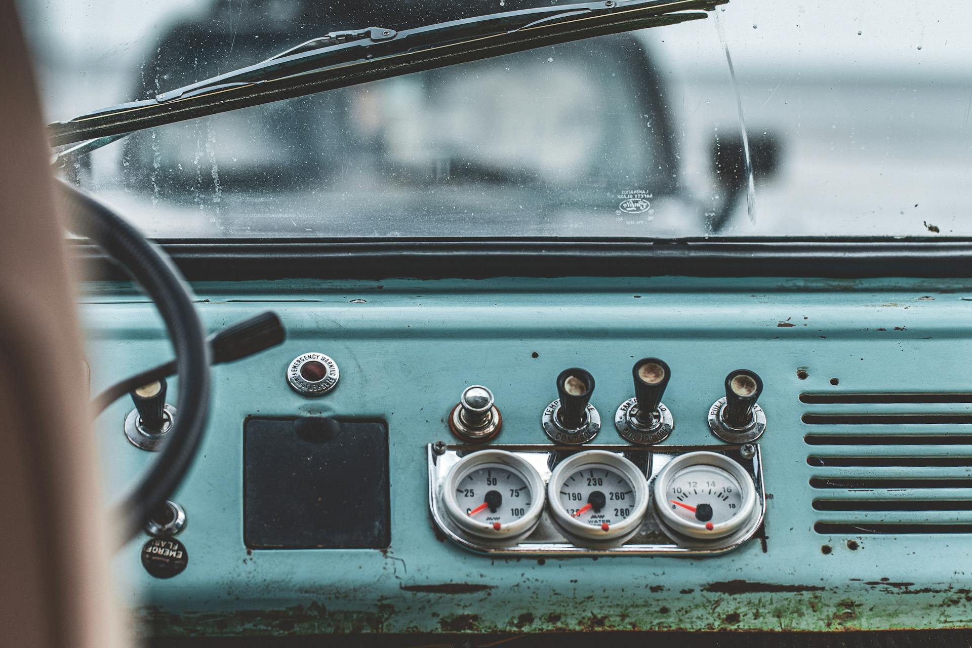 Detailed view of a vintage car interior showing dashboard gauges, steering wheel, and windshield.