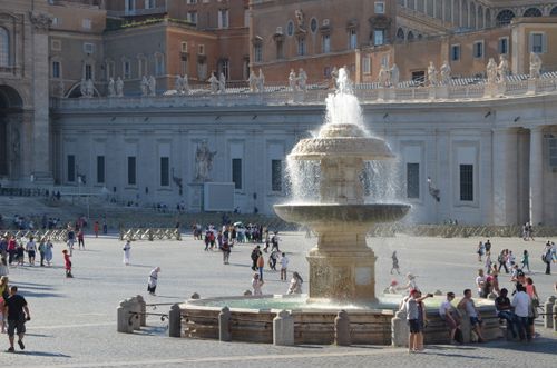 Free Tourists gather around the historic fountain at St. Peter's Square in Vatican City. Stock Photo