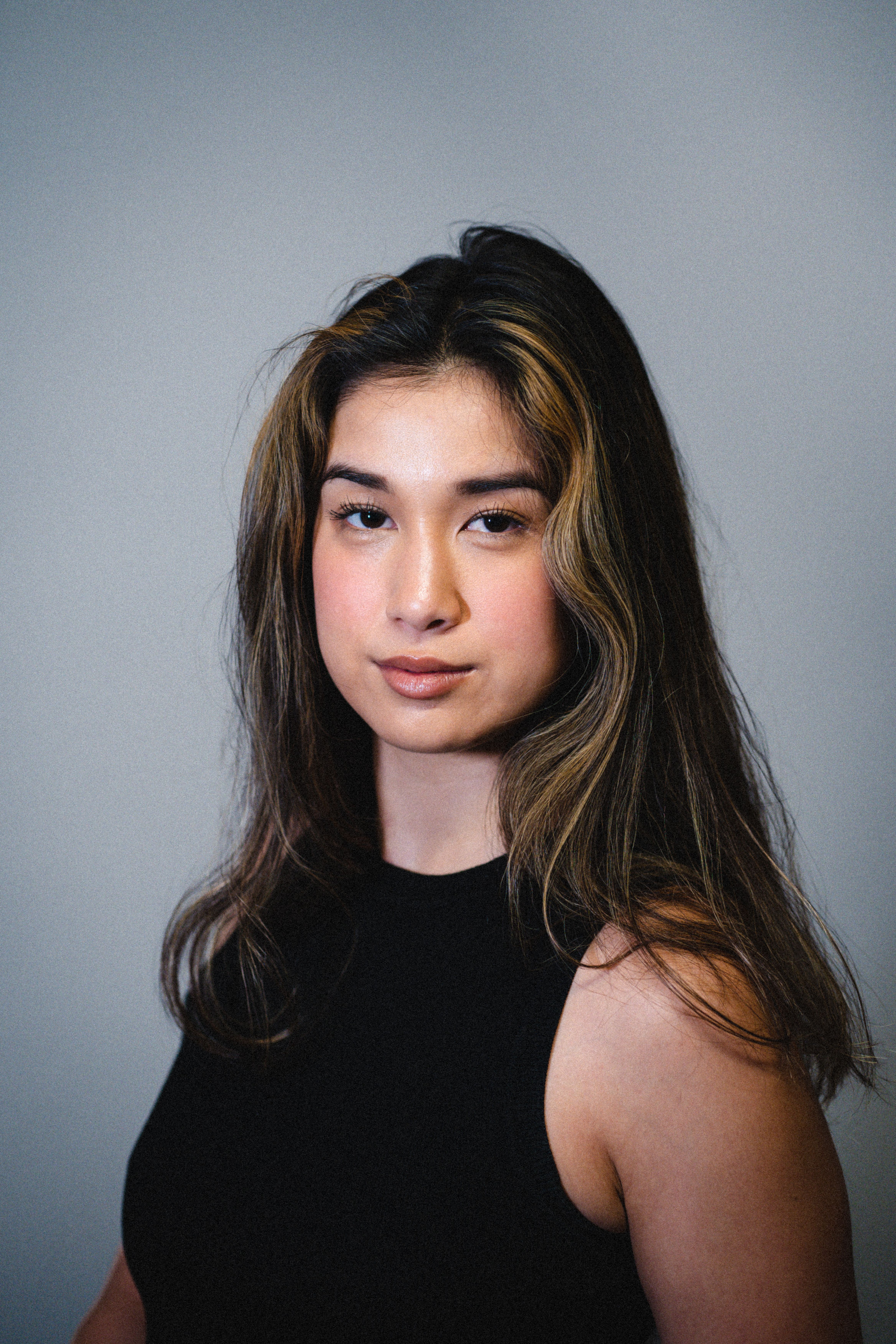 Studio portrait of a confident brunette woman in a black blouse, posing with poise.