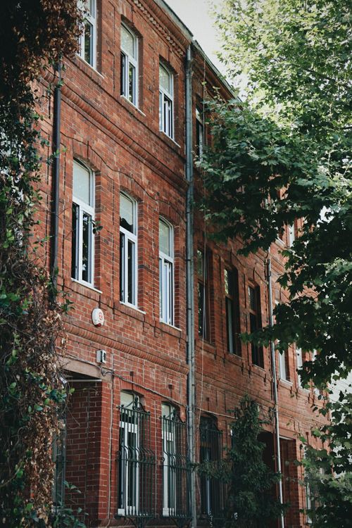 Free Charming brick residential building amidst lush greenery in urban setting. Stock Photo