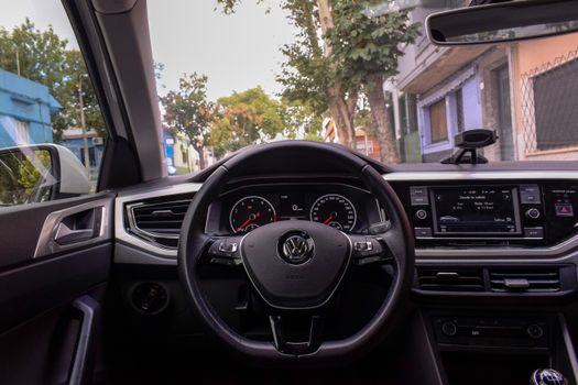 A view of a Volkswagen car interior highlighting the dashboard and steering wheel in an urban setting.