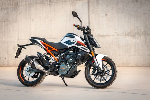 Free A sleek motorcycle parked against a concrete wall in an urban environment, showcasing modern design. Stock Photo