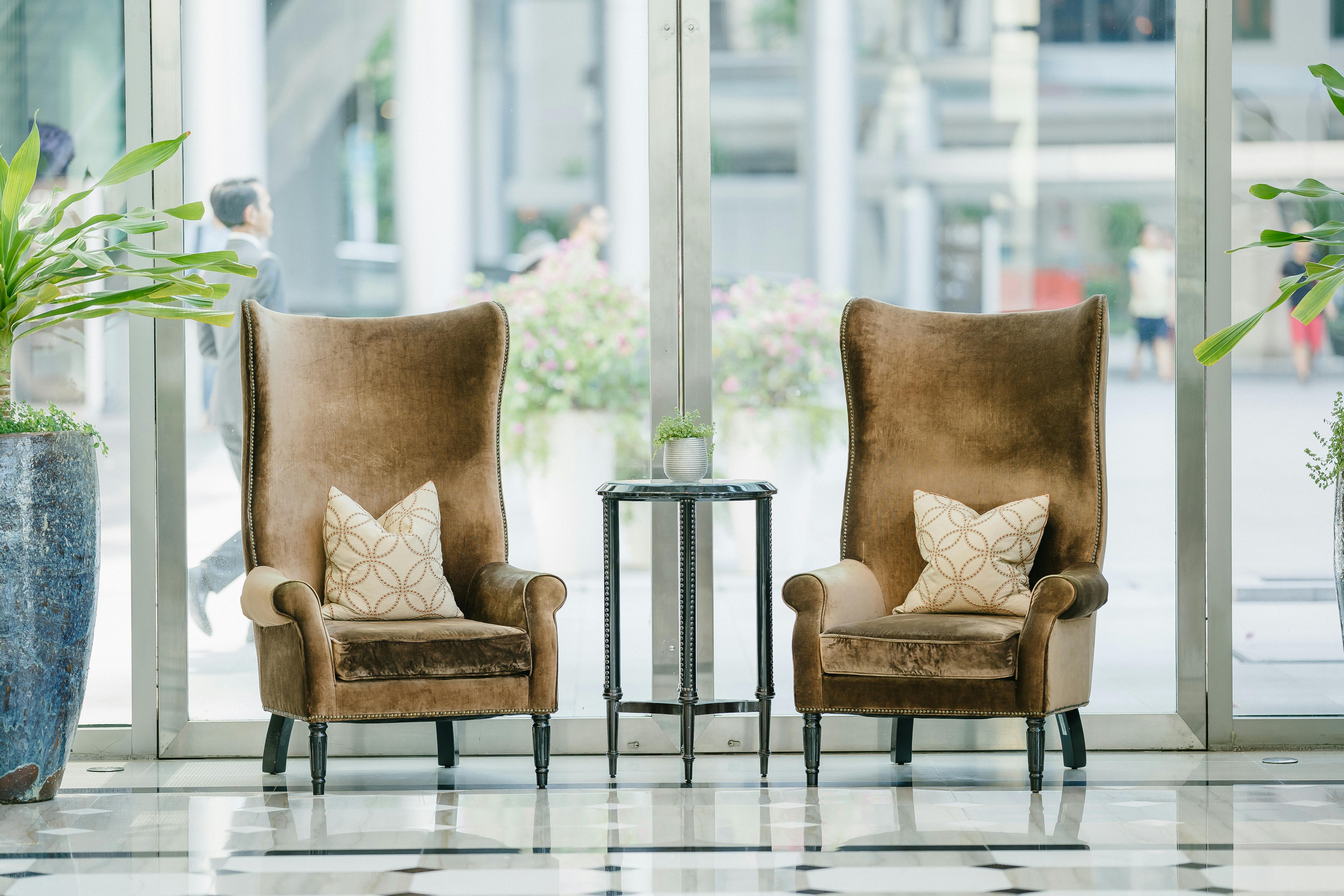 Photo of two brown sofa chairs near glass window