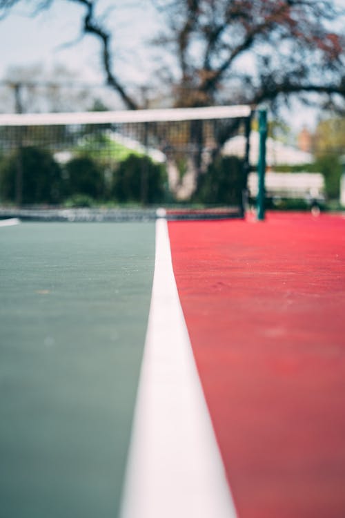 Selective Focus Close-up Photo of Empty Red and Green Tennis Court With View of Tennis Net