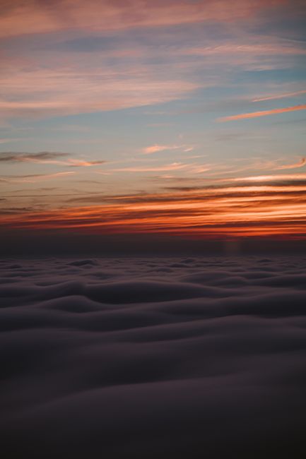 Capture of a vibrant sunset over a vast cloudscape, creating a dramatic horizon view.