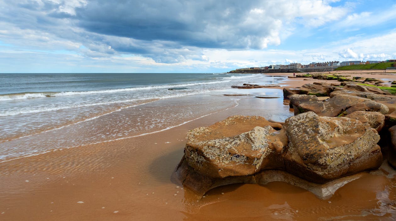 A beach with rocks and sand under cloudy skies