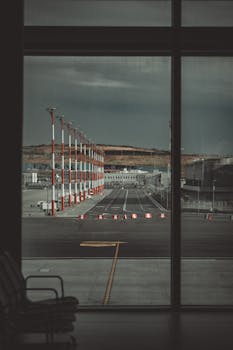 View from an airport lounge through large windows, overlooking an empty tarmac and streetlights.