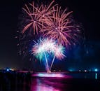 五彩缤纷的烟花在水面绽放，灯光倒映在夜空之中