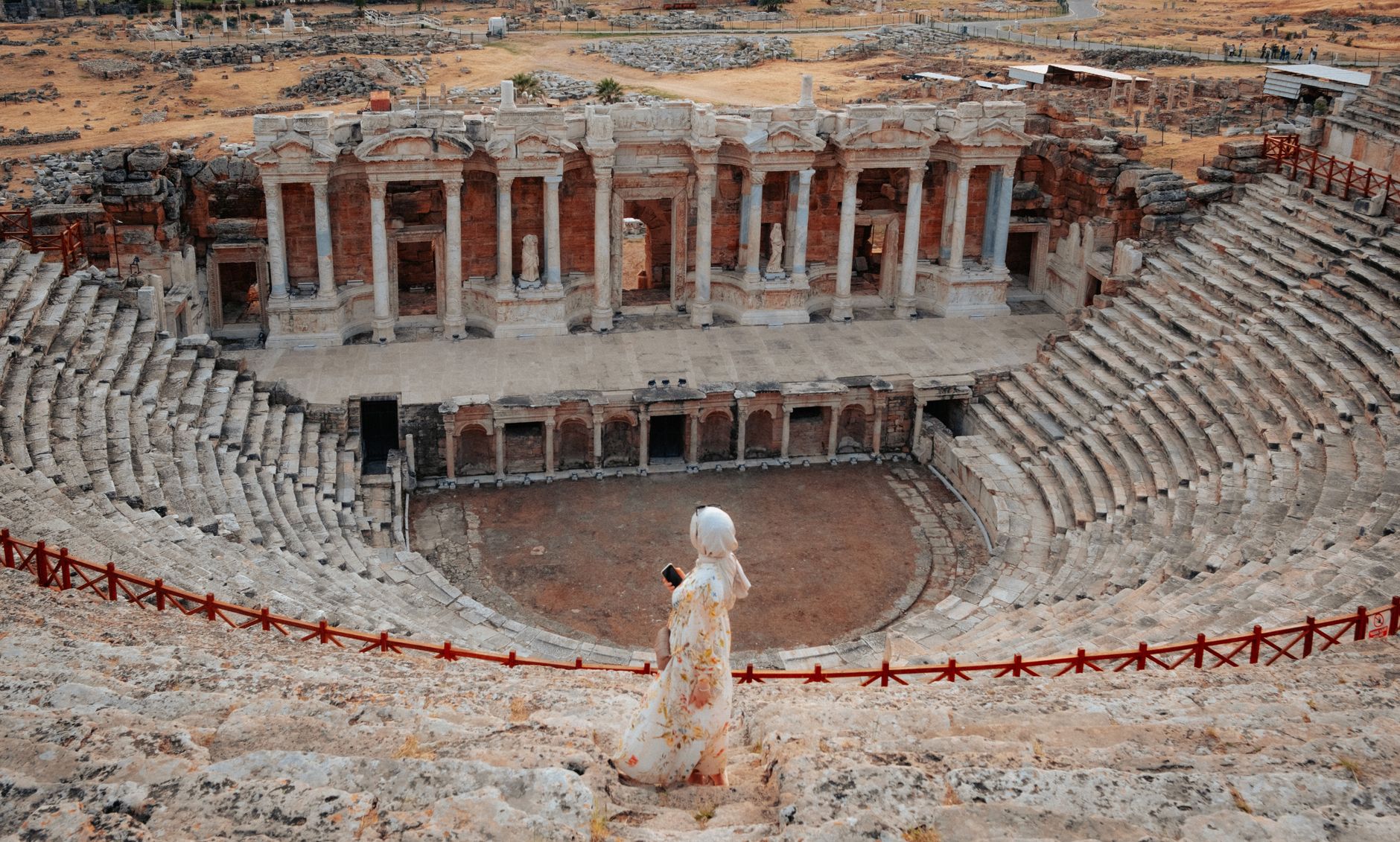 Woman admiring the grand architecture of the ancient Hierapolis theater in Pamukkale, Türkiye.