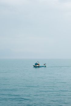 Calm fishing boat drifting on serene Black Sea near Akçaabat, Trabzon, Türkiye.