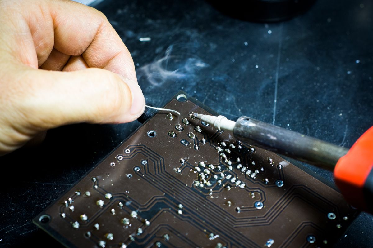 Hand carefully soldering a small ceramic capacitor onto a printed circuit board