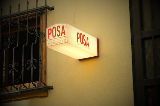Brightly lit Posa Coffee Roastery sign on a building wall, creating a warm ambiance.