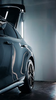 A modern luxury car with open trunk in a dimly lit indoor garage, showcasing its sleek design.