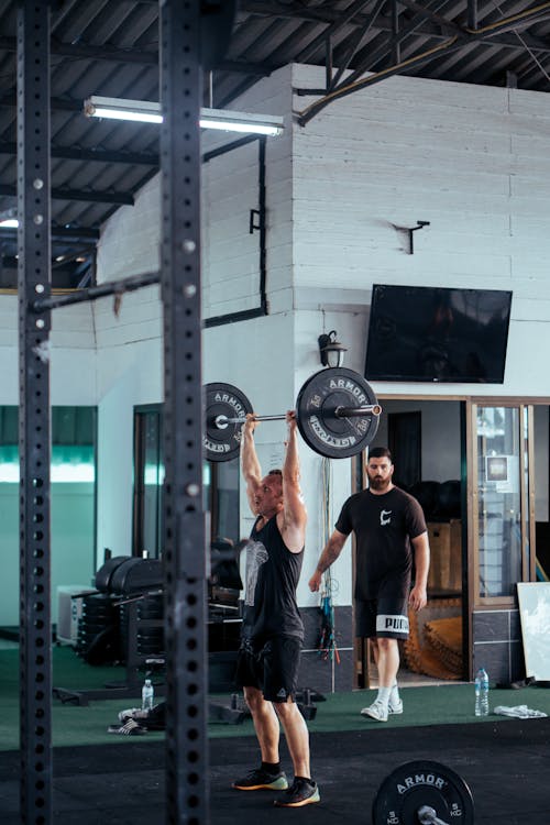 Free Man In Black Tank Top Lifting Barbell At The Gym Stock Photo