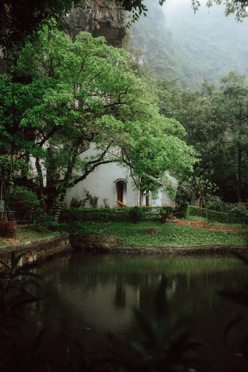 A small white house sits next to a pond