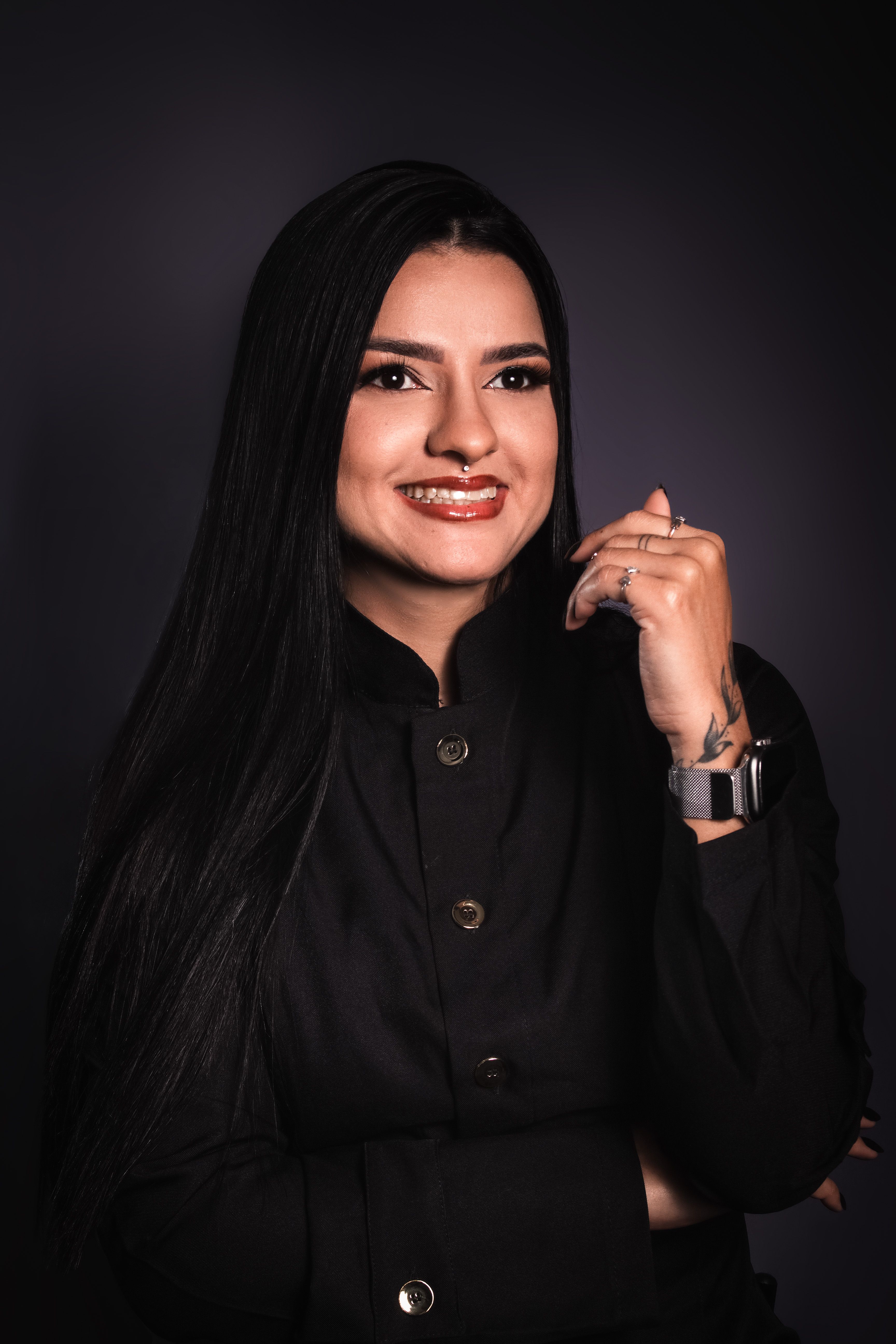 Portrait of a smiling woman in a black blouse, posing with elegance in a studio setting.
