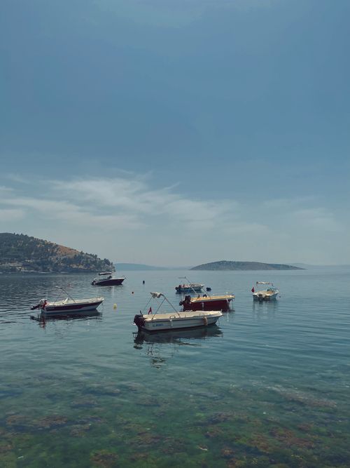 Free Scenic view of fishing boats floating on calm sea against distant islands. Stock Photo