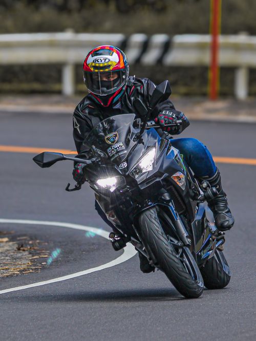 Free Motorcyclist in leather gear rides a sleek motorcycle around a sharp curve on an open road. Stock Photo