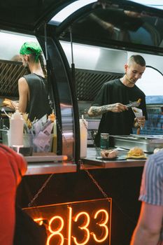 Street food vendor serving customers at a vibrant night market stall.