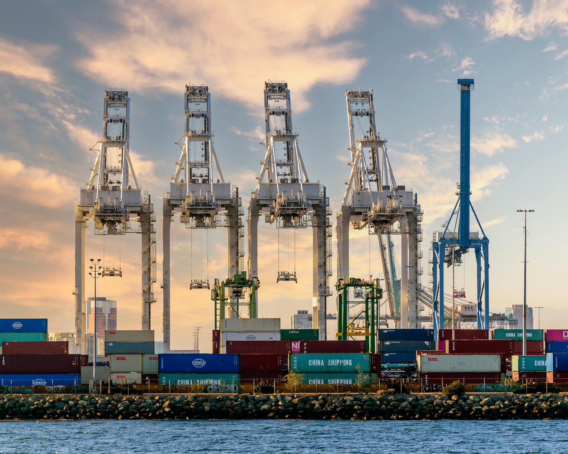A vivid illustration of port logistics with cranes and shipping containers under a striking sky.