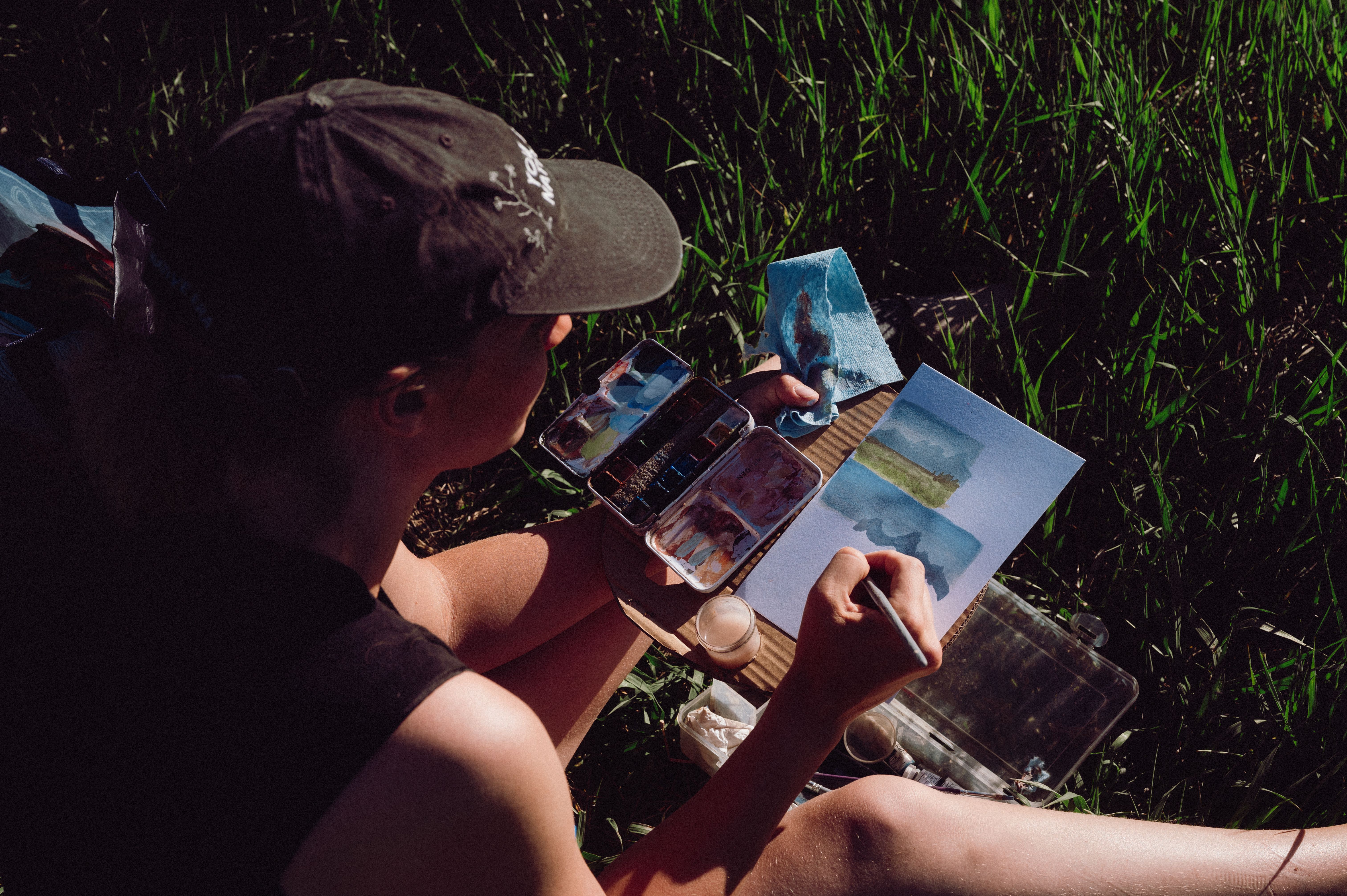 An artist painting a landscape outdoors, engaged with the surrounding natural environment