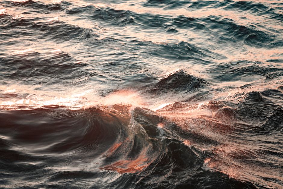 Captivating view of ocean waves at dusk with sunlight reflections and splashes