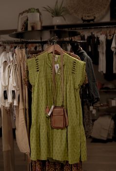 Stylish green bohemian dress on display with accessories in an indoor boutique setting.