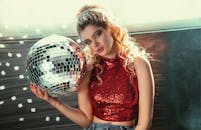 一位穿着红色亮片上衣的时尚女性手握迪斯科球，散发着魅力与诱惑