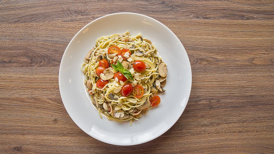 Handmade pasta with mushrooms and cherry tomatoes in a white bowl