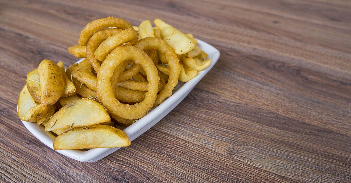 Uma deliciosa porção de anéis de cebola crocantes e batatas fritas em uma mesa de madeira.