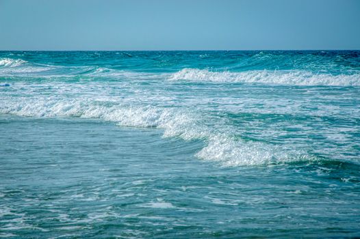 Dynamic seascape with turquoise waves and clear horizon captured on a sunny day.
