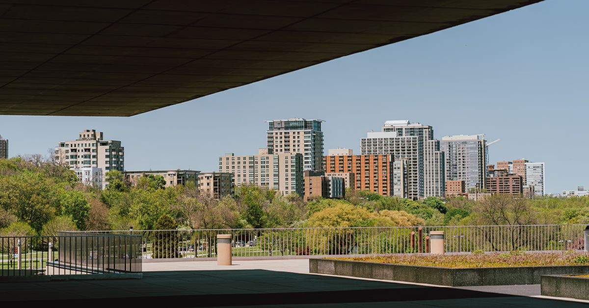 City skyline with modern skyscrapers framed by a park view and urban railings.