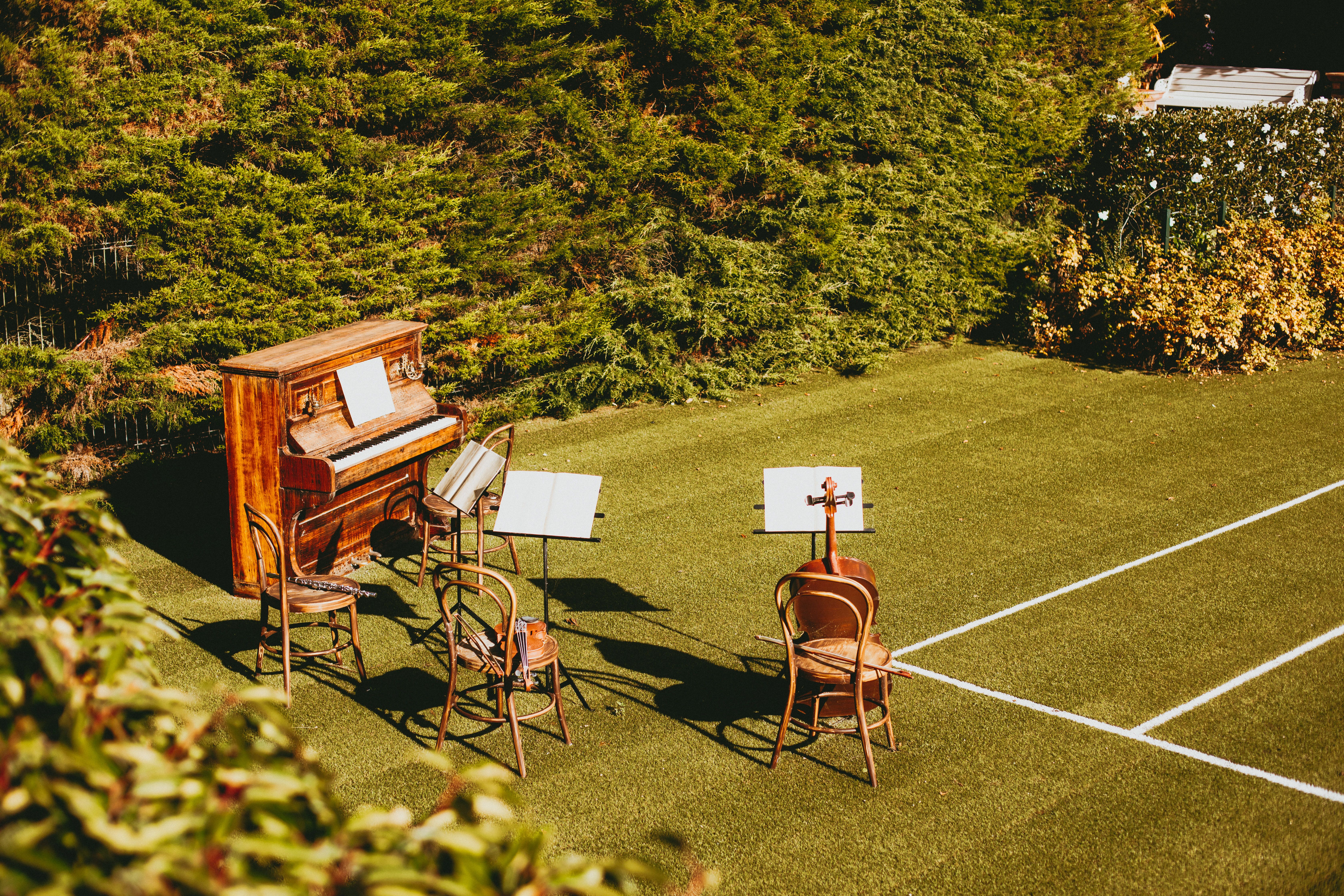 Outdoor music setup with piano and chairs on grassy lawn, ideal for events.