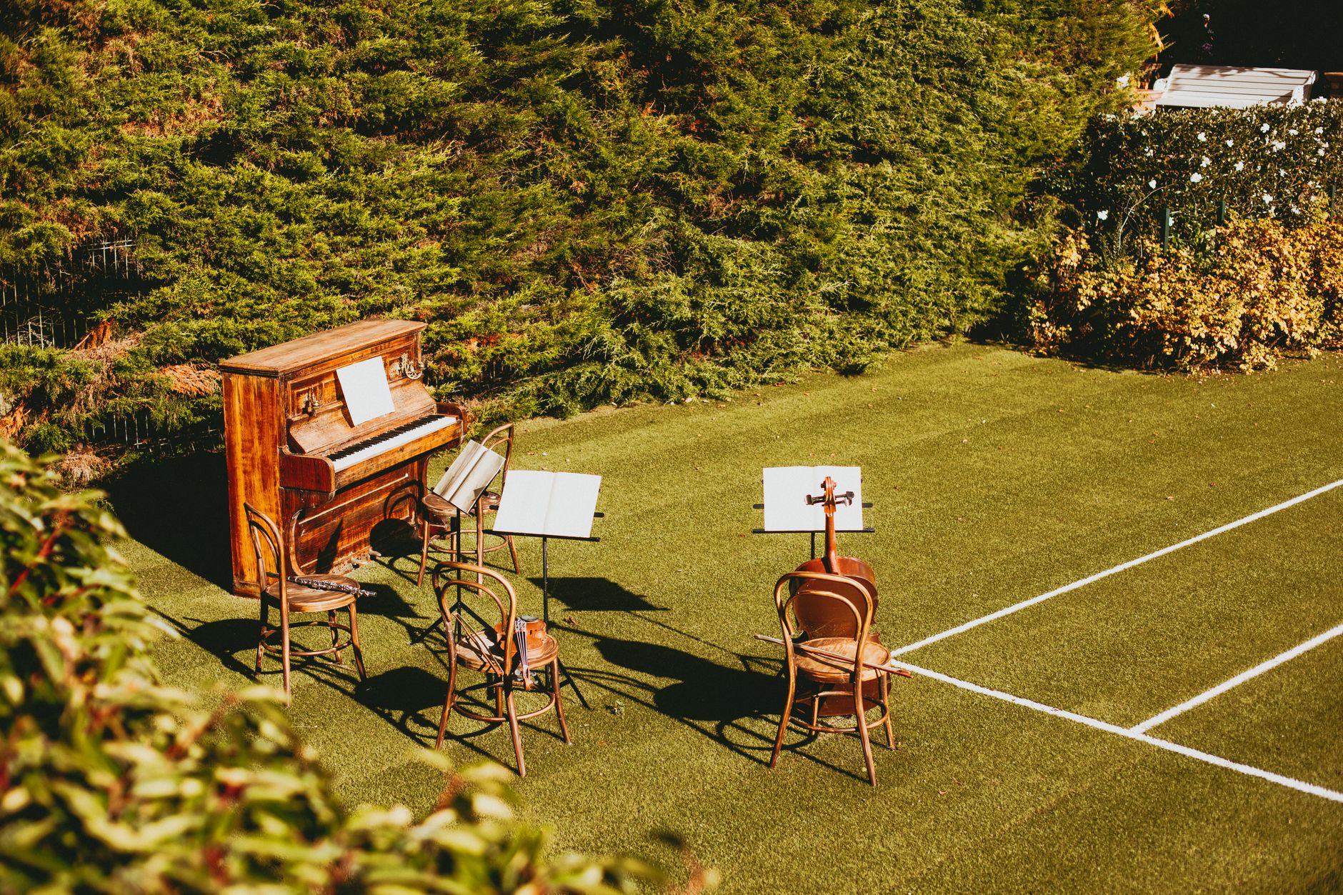 Outdoor music setup with piano and chairs on grassy lawn, ideal for events.