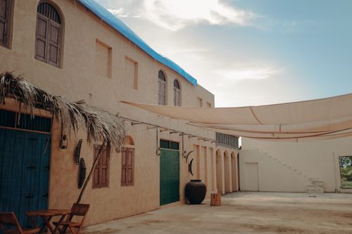 Free Explore a rustic courtyard with distinct architecture, featuring wooden windows and natural shades under a bright sky. Stock Photo