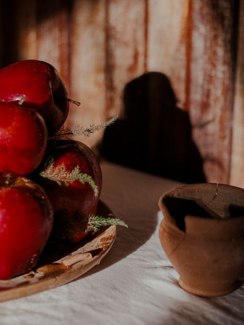 Free Moody still life of red apples on a wooden tray with pottery in warm light. Stock Photo
