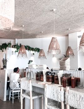 Bright and airy restaurant interior featuring woven lamps and rustic decor, perfect for a cozy dining experience.