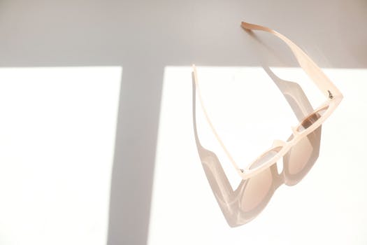 这副别致的太阳镜在浅色表面上投下戏剧性的阴影，非常适合夏季时尚