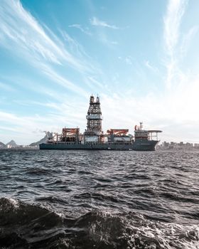 Large offshore oil rig ship on open sea with dramatic sky and skyline.