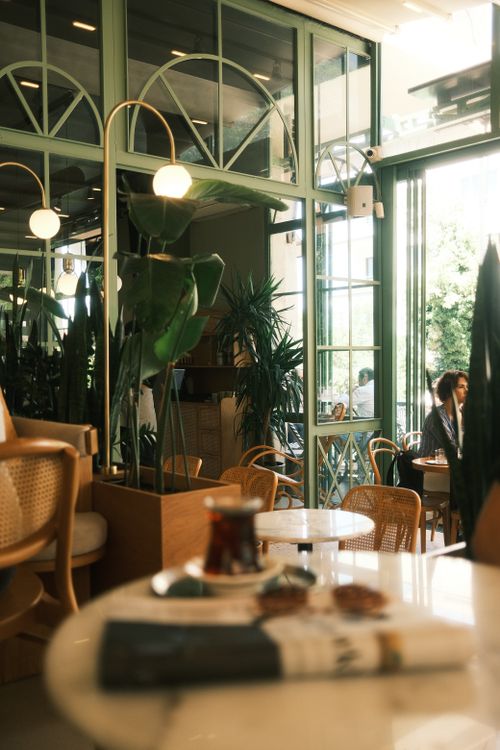 Free Warm and inviting cafe interior with natural plant decor and comfortable seating arrangement. Stock Photo