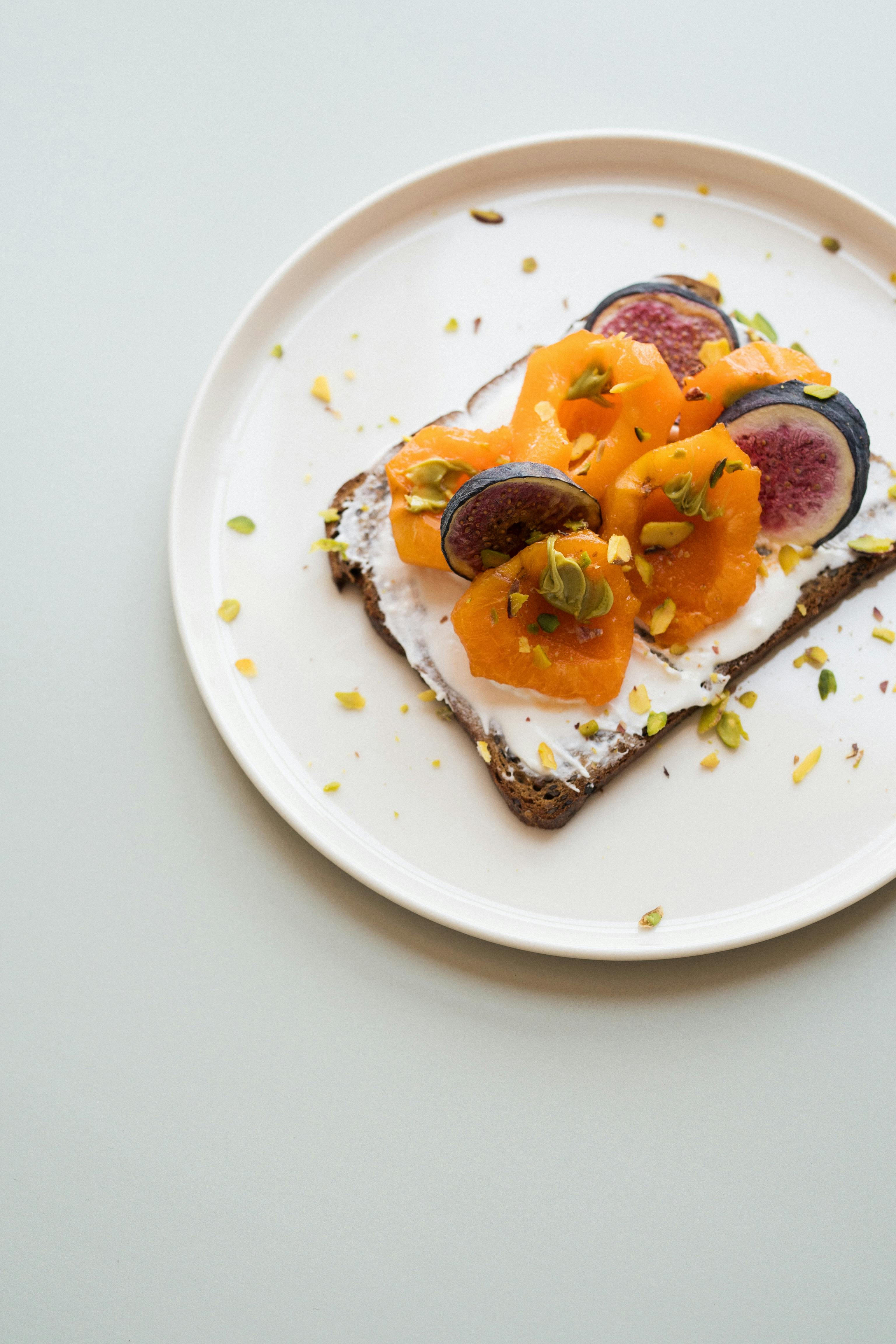 Fresh fig and persimmon toast on a white plate. Perfect for a healthy breakfast.