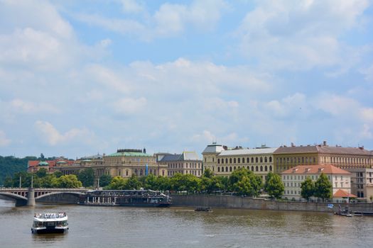 A picturesque view of Prague with the Vltava River, historical buildings, and a bridge.