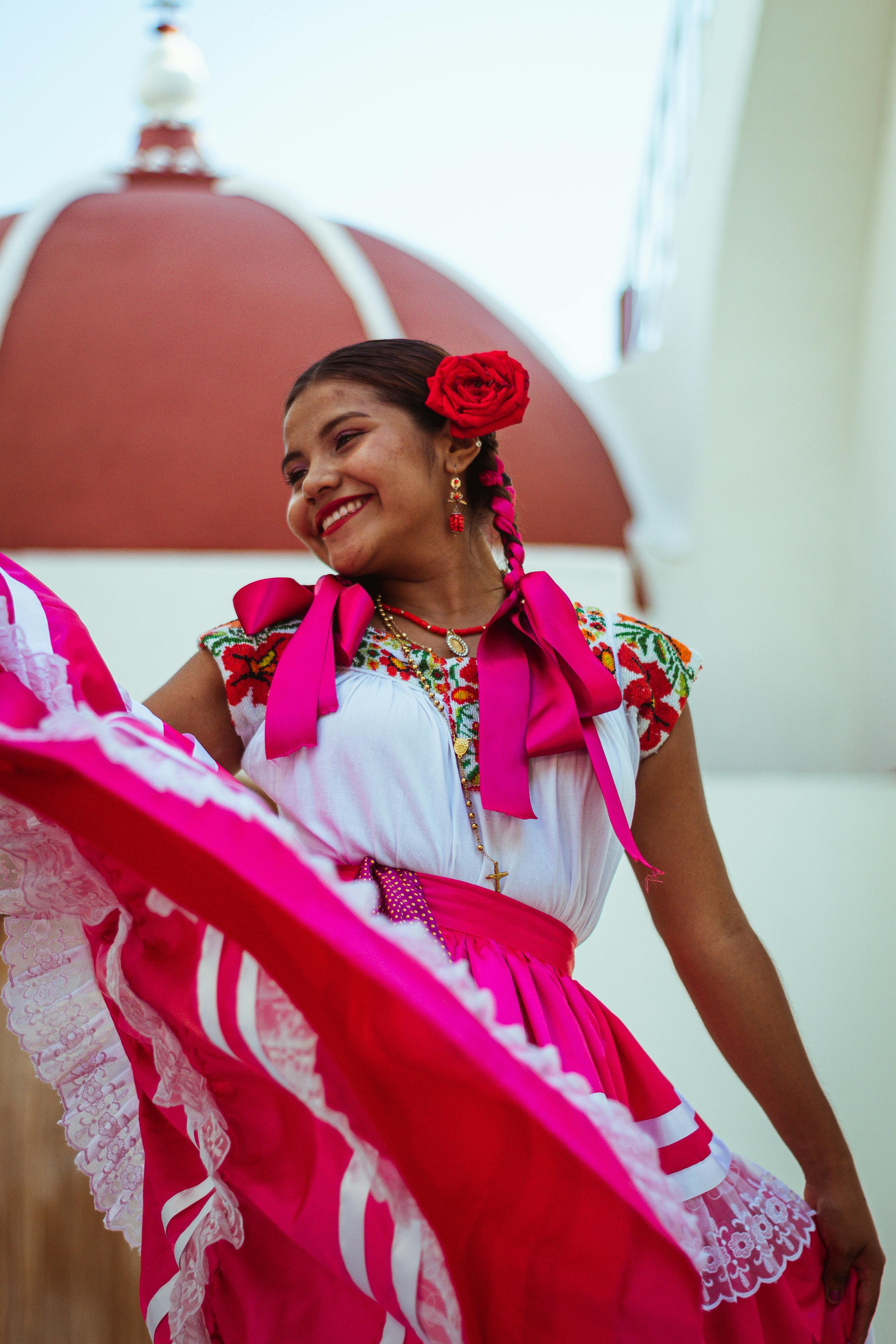 a young woman in a mexican dress dances in front of a church