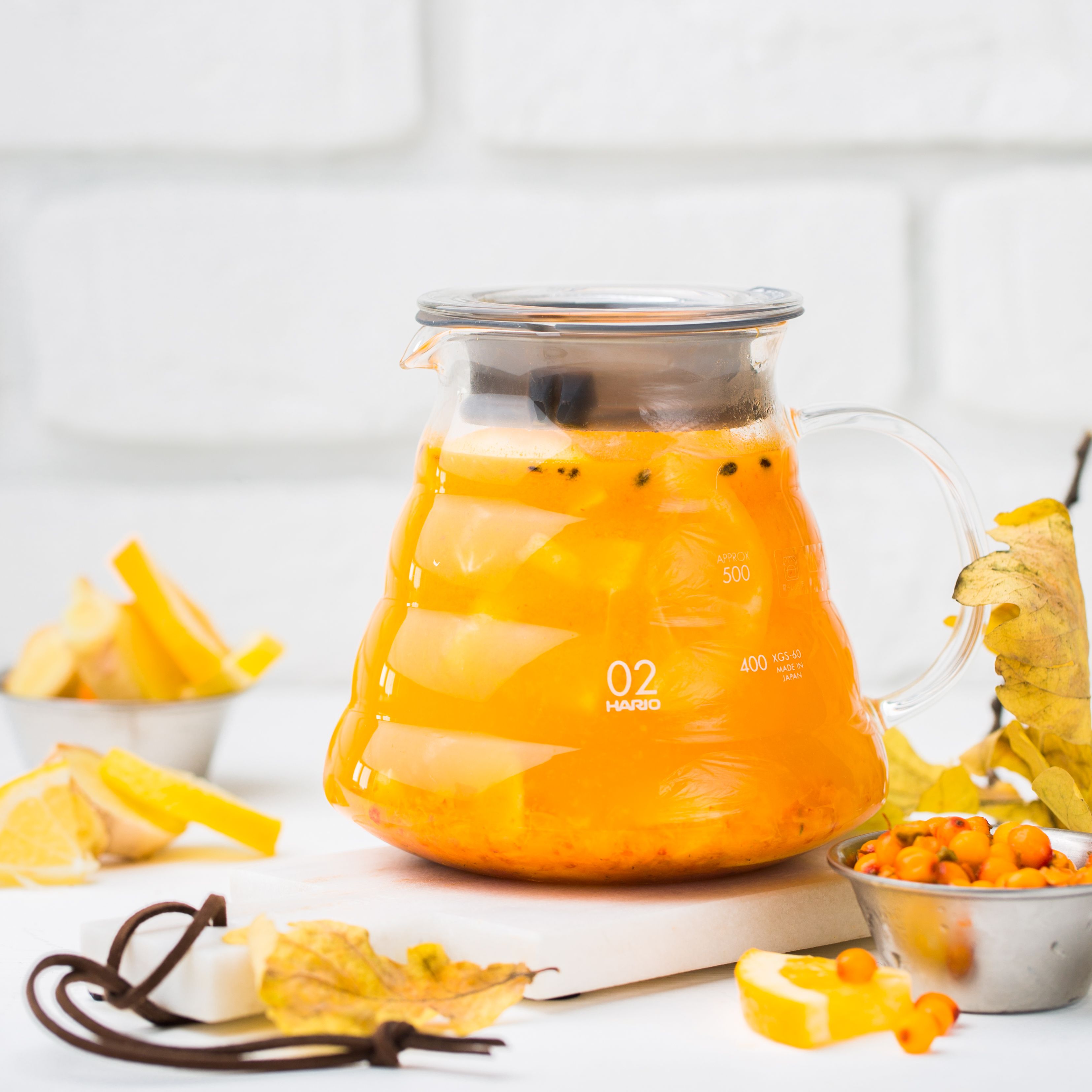 Vibrant orange sea buckthorn tea in a glass teapot, perfect for a warm autumn day.