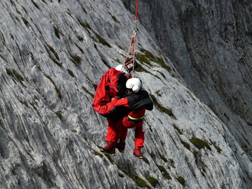 Two People Rappelling Near Grey Rocks