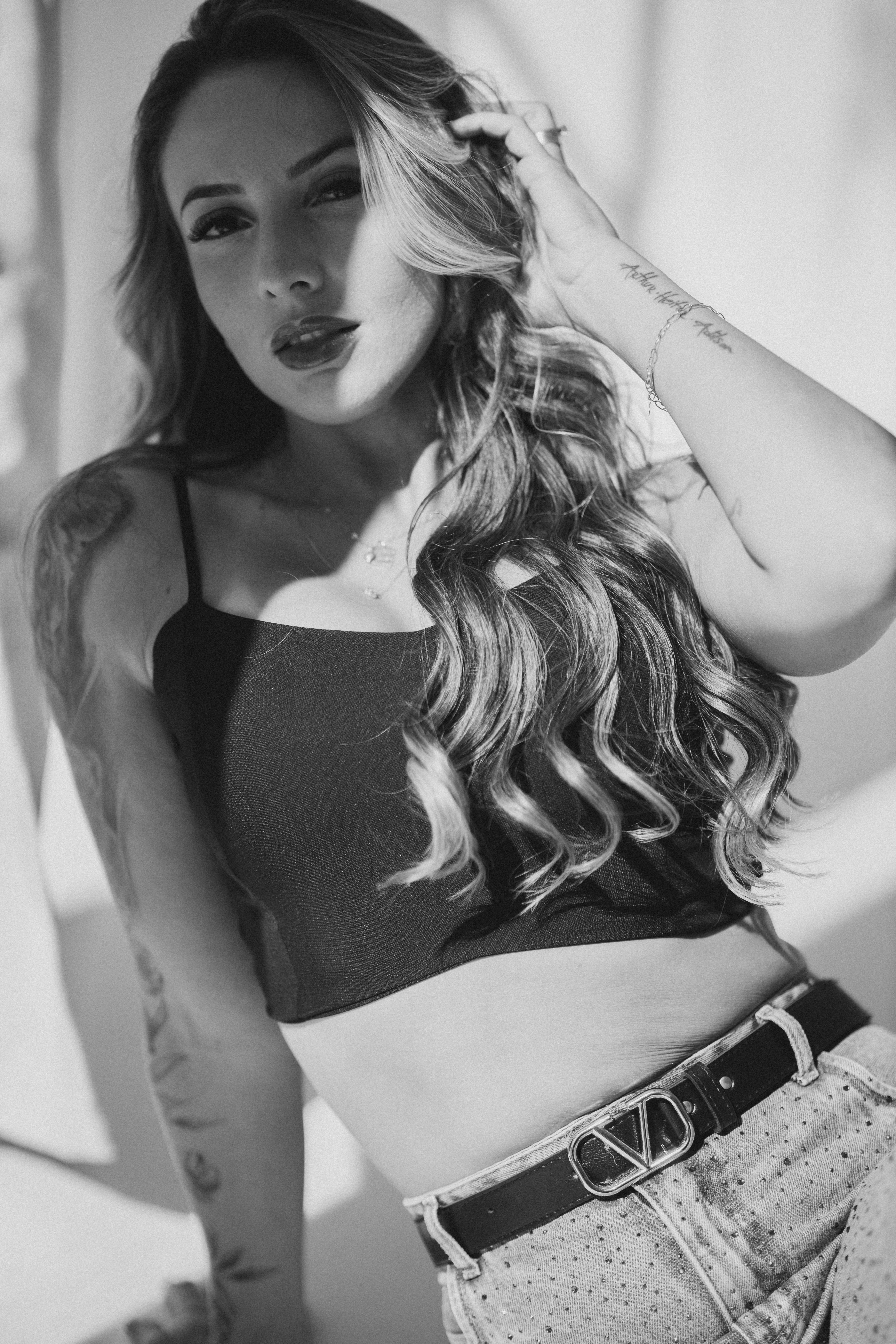 Black and white portrait of a young woman with long hair posing casually in a studio.