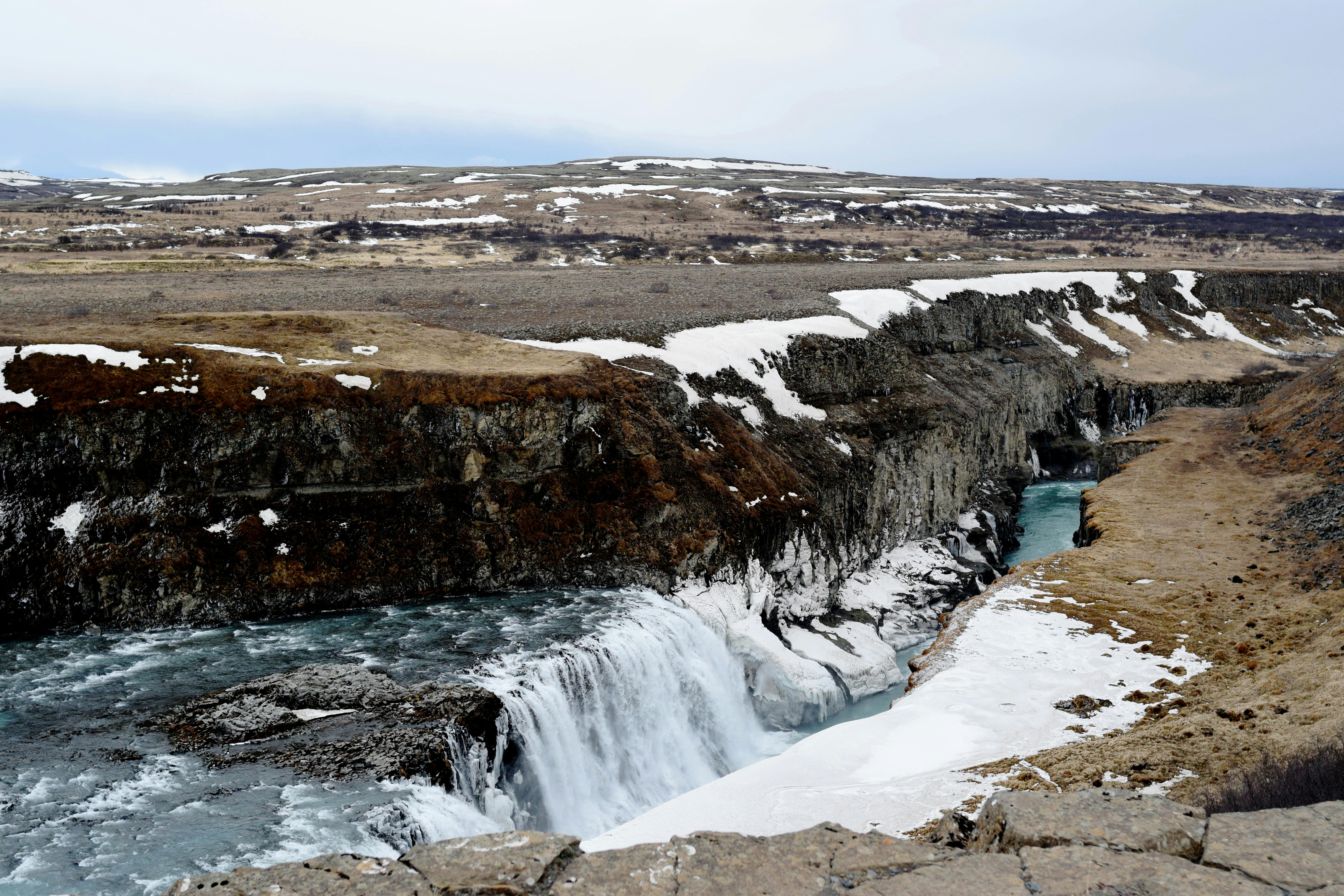 Majestic view of Gullfoss waterfall in Iceland, surrounded by snowy landscape, winter season.