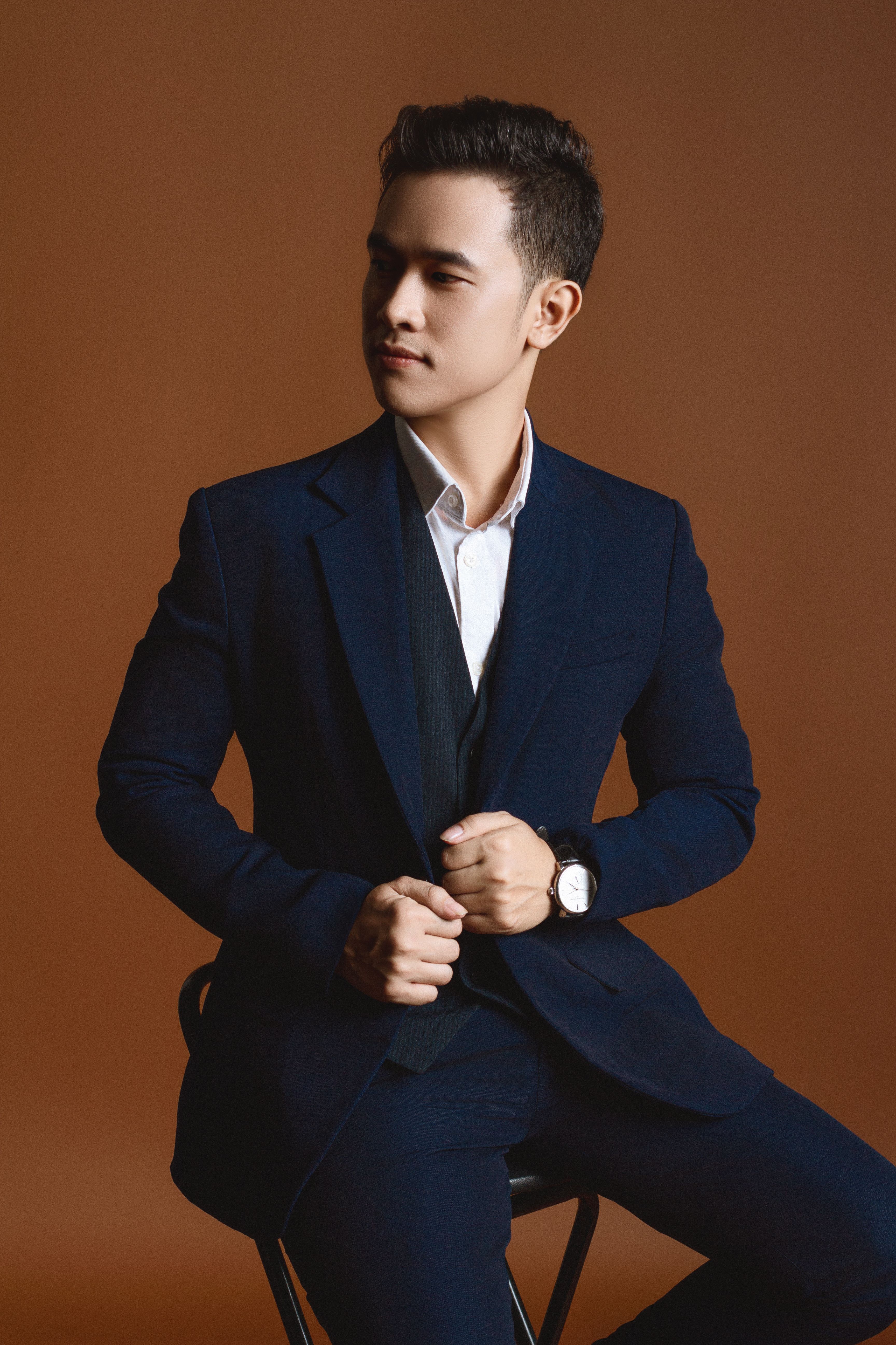 Elegant young man in a tailored suit posing in a professional studio setting.
