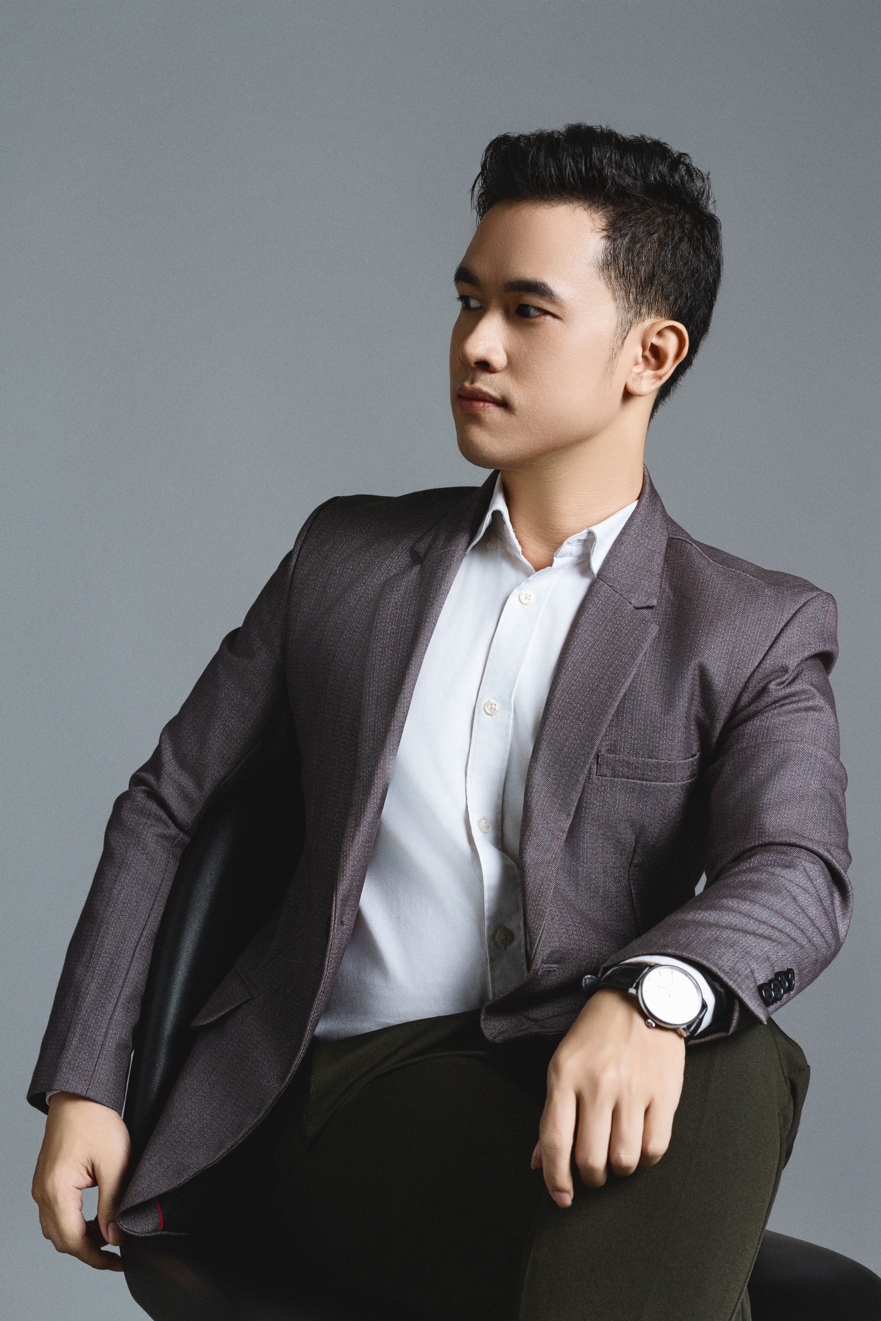 Well-dressed man in a suit posing elegantly in a studio setting.