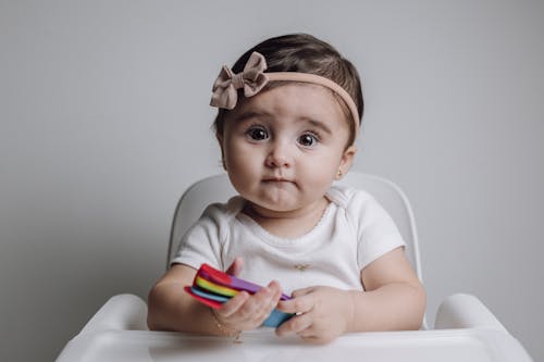 Free A baby girl sitting in a high chair with a colorful toy Stock Photo